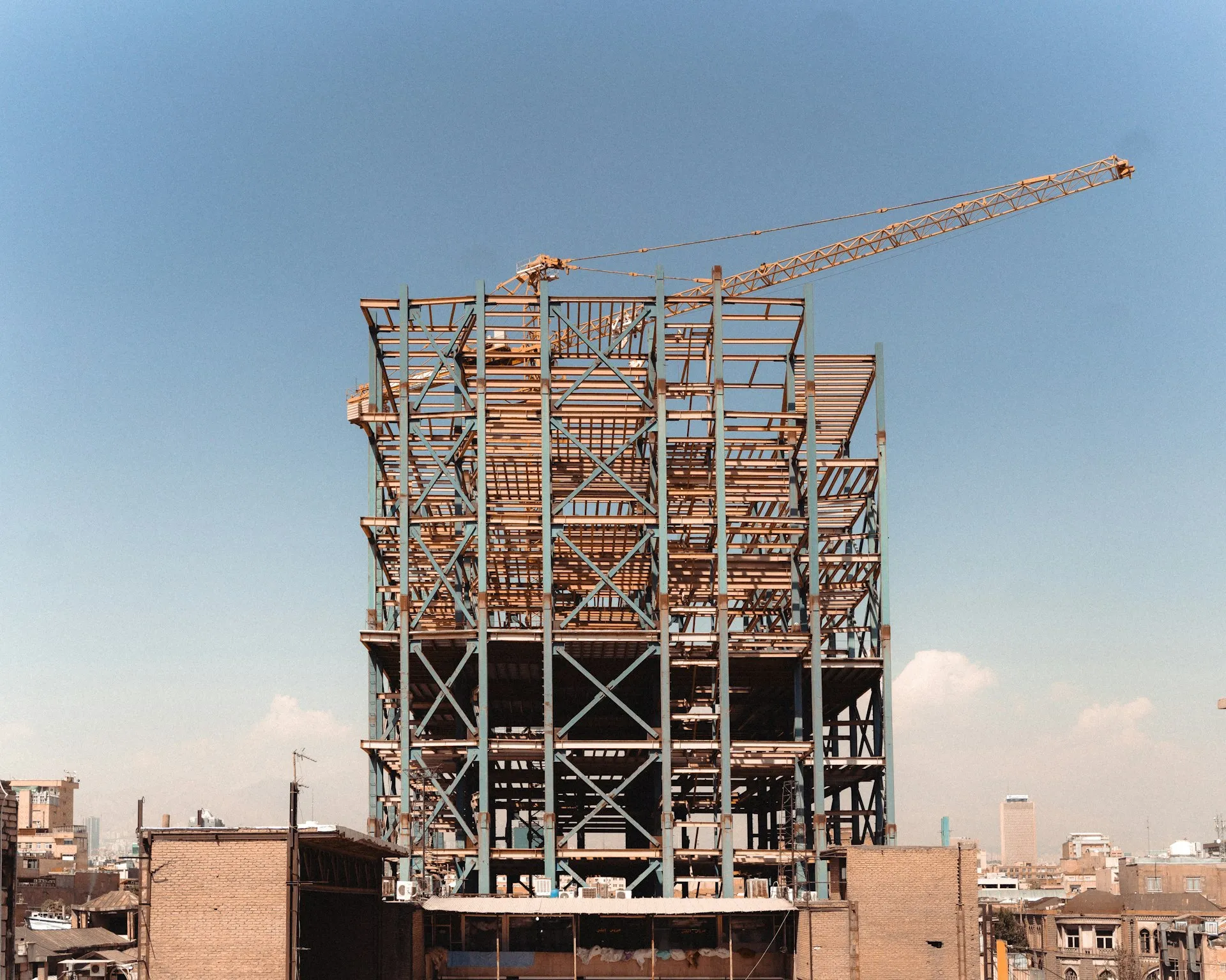 Steel structural framework of a building under construction against a clear blue sky