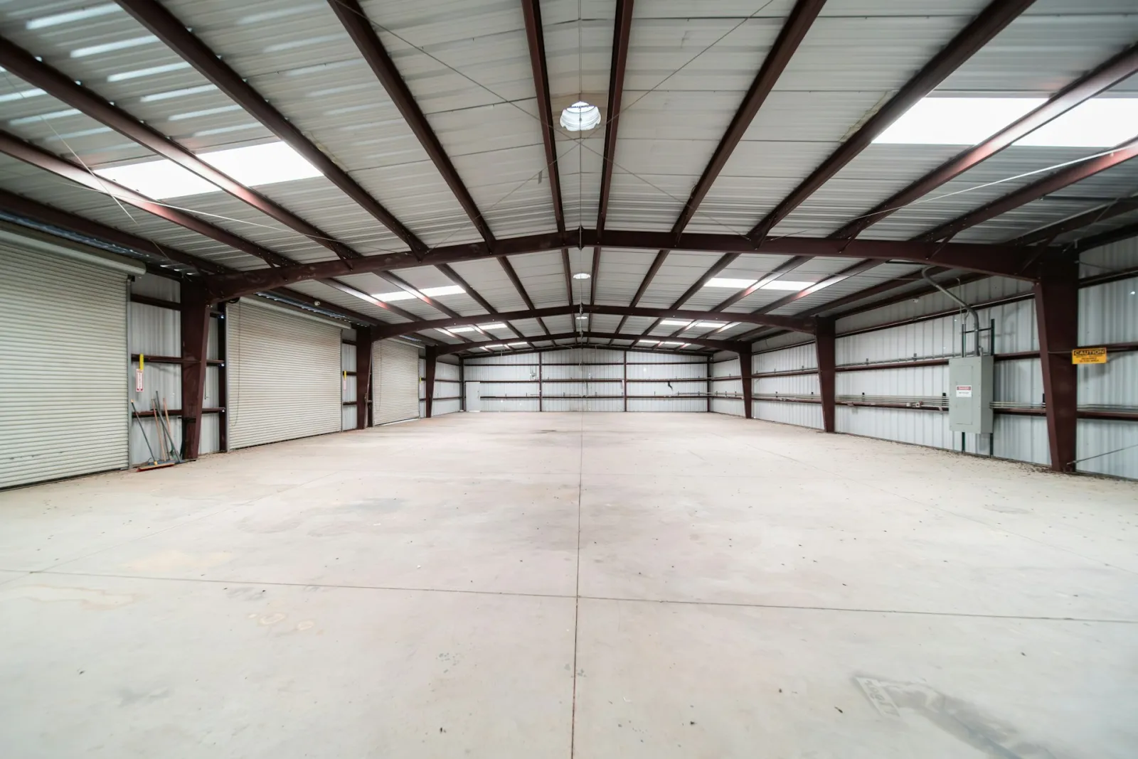 Inside a large empty steel-framed warehouse with a clear-span roof