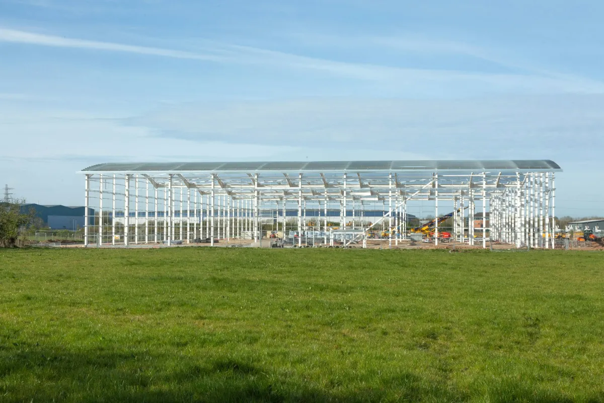 Steel portal frame building under construction in an open field