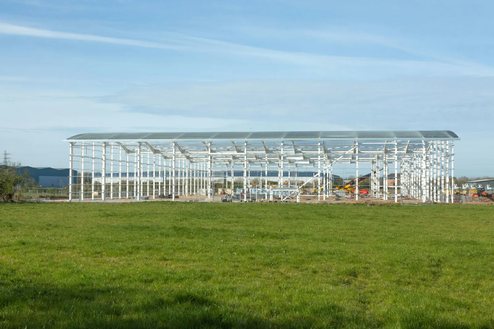 Steel portal frame building under construction in an open field