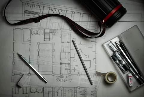 Building drawings on a desk with drafting pencils, a metal ruler and a drawing tube